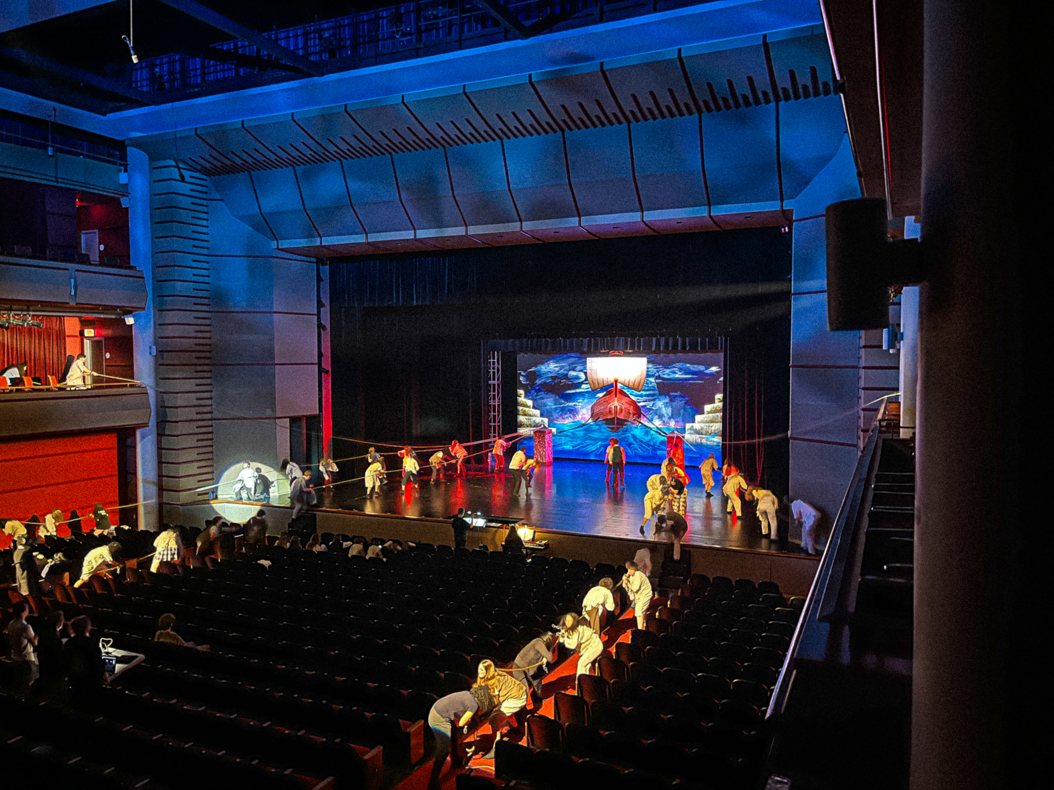 Les Misérables company extending through the auditorium under blue and red lighting