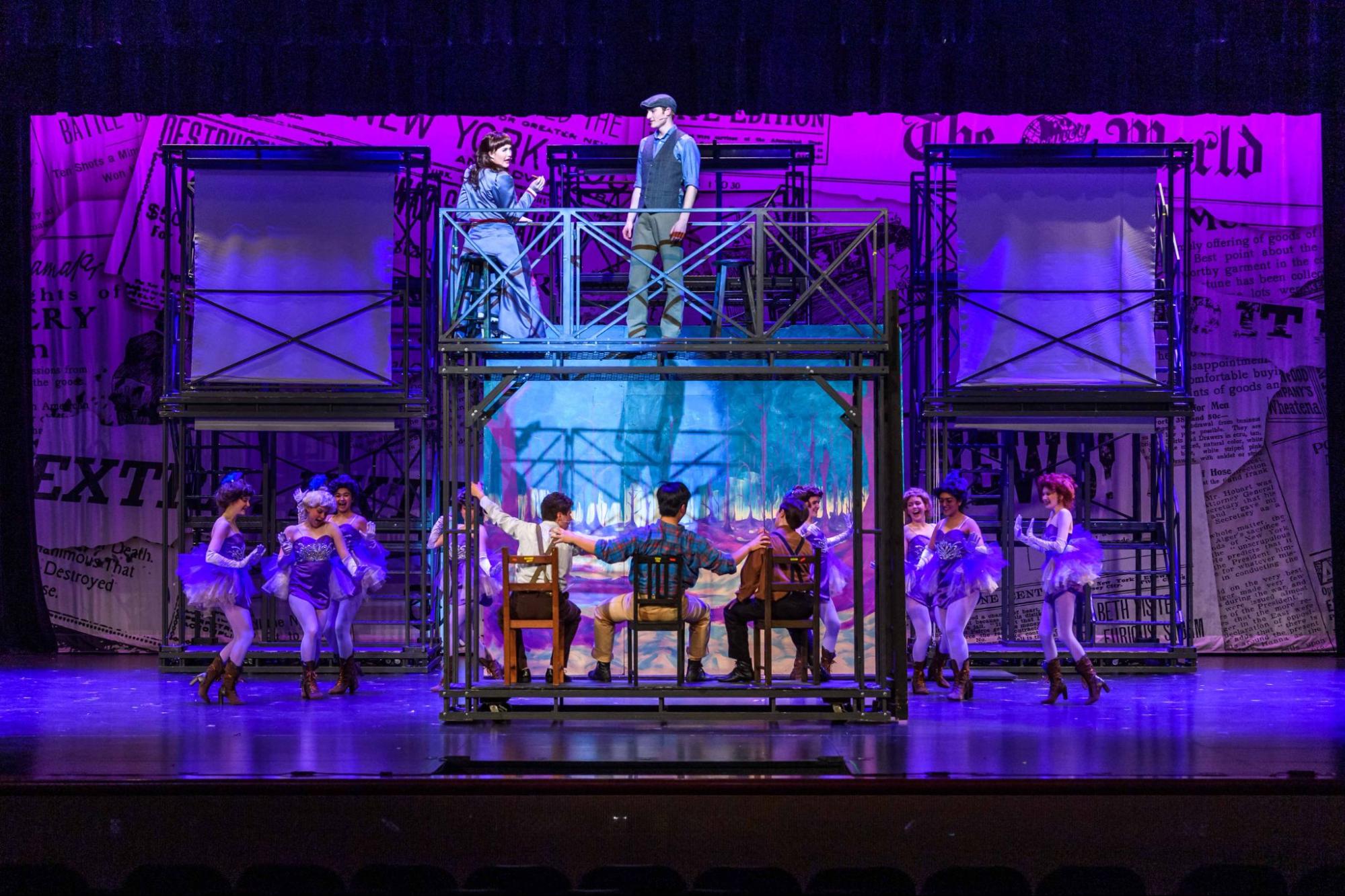 Newsies production with metal towers and a purple cyclorama